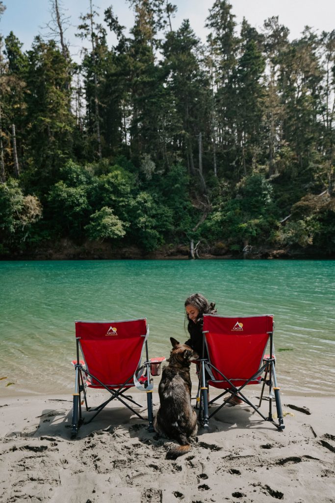 girl and dog sitting in front of turquoise river in Mendocino California