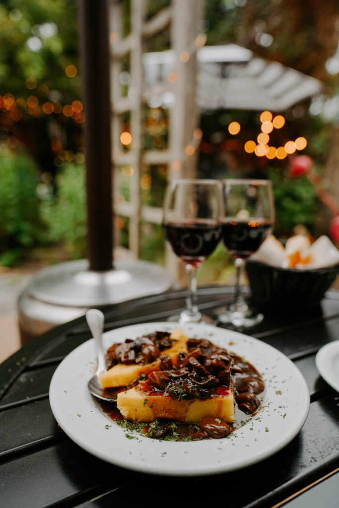 Dinner plate with two glasses of wine and twinkly lights in garden patio