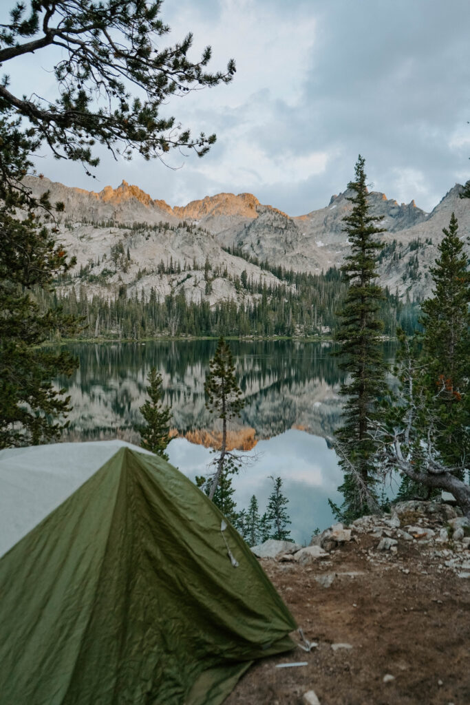 Tent overlooking a blue lake with mountains in the distance