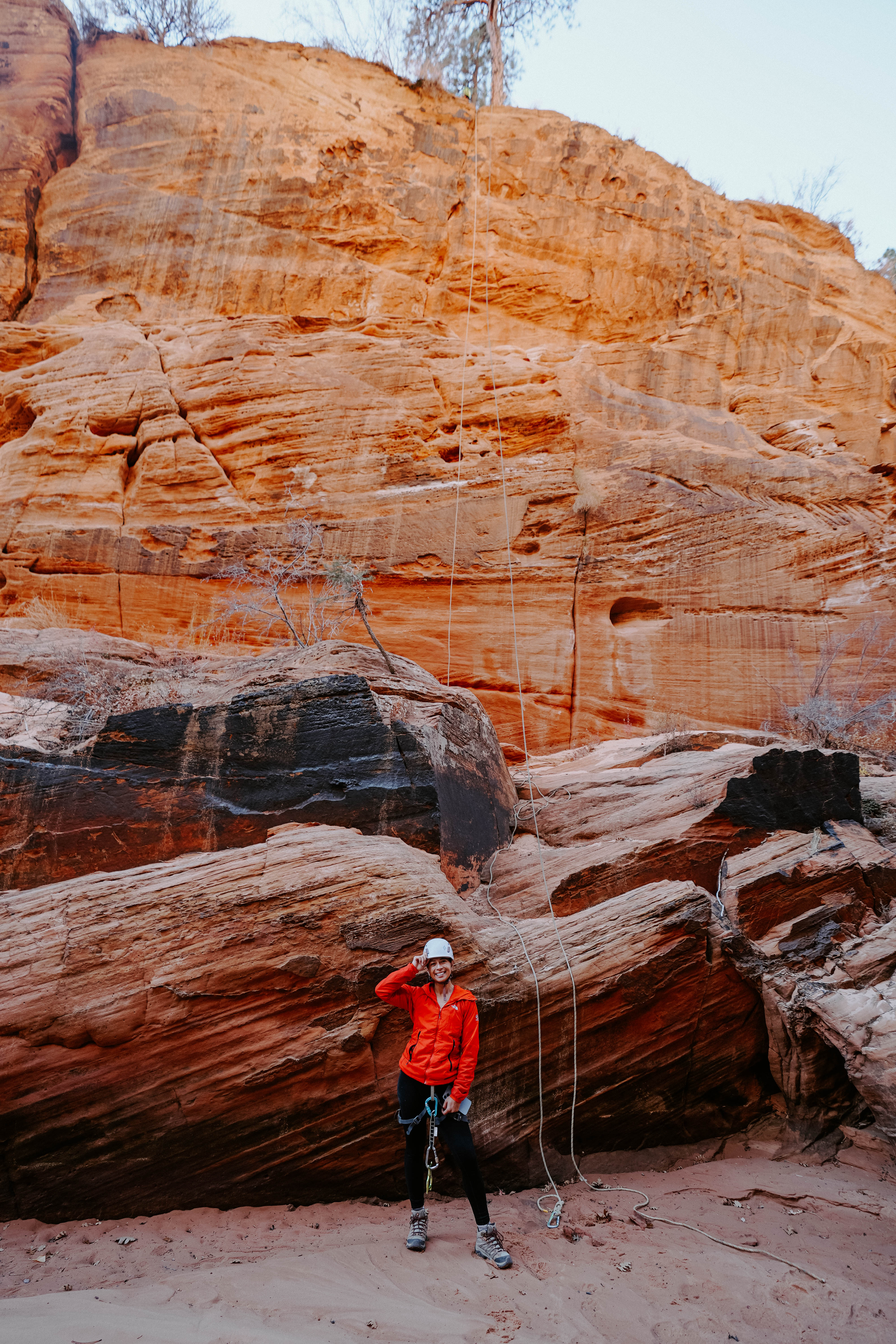 Girl standing beneath tall canyon with a canyoneering rope