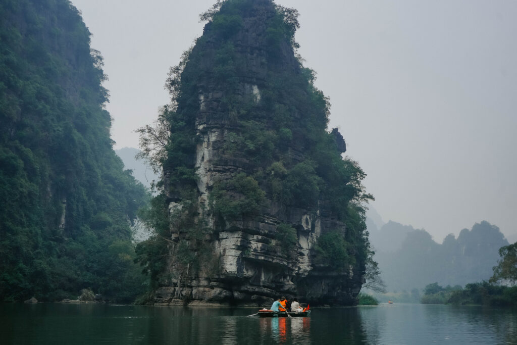 Small wooden boat in front of a limestone rock in Ninh Binh