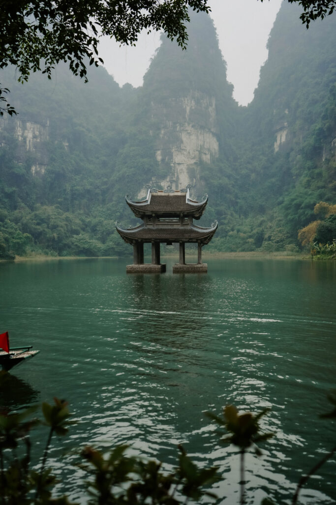 Ancient Temple in the middle of a lake and towering mountains in Ninh Binh