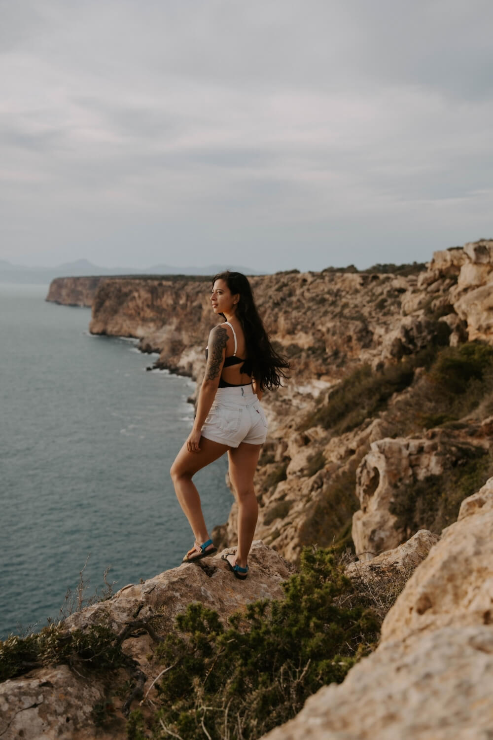 girl in white shorts looking at a view over mallorca