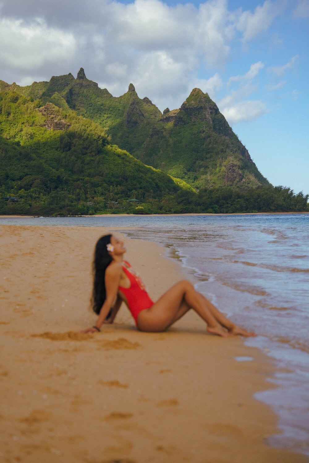 girl in a red swimsuit sitting on tunnels beach kauai